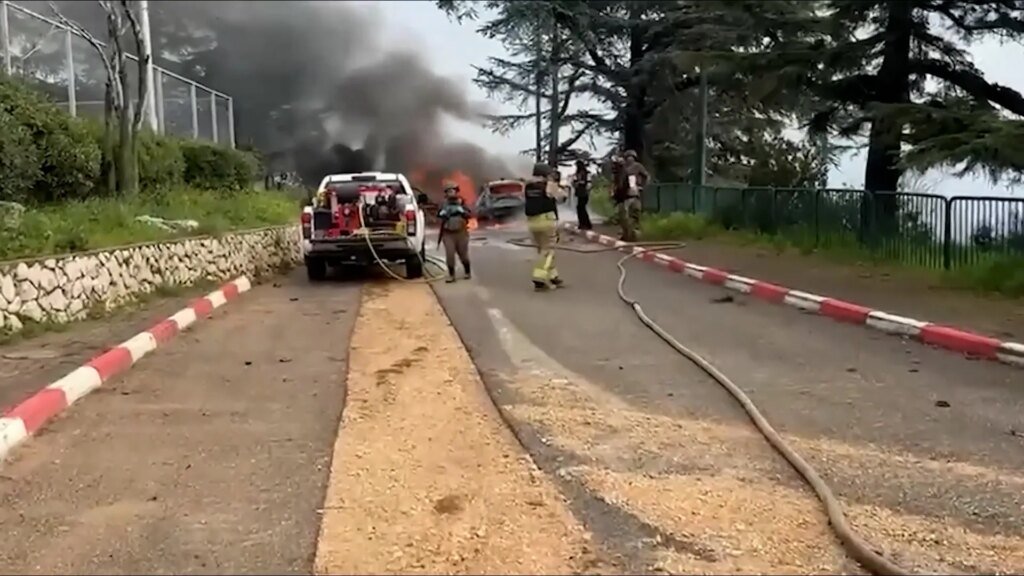 Los bomberos israelíes apagan incendios en vehículos tras el ataque con misiles desde Líbano.